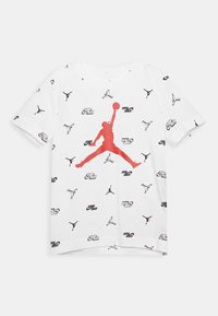 Vit bomull t-shirt med en stor röd Jumpman-logotyp i mitten, med upprepade svarta logotyper och silhuetter över hela. Korta ärmar.