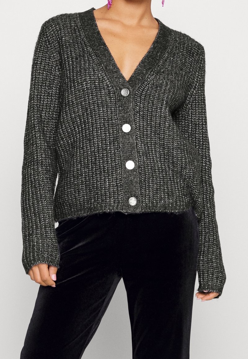 Objemný šedý kardigan s výstřihem do V, dlouhými rukávy a pěti velkými stříbrnými knoflíky. Texturovaná pletenina a zkrácený lem.