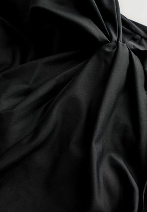 Crna tkanina s glatkom teksturom, koja sadrži blage nabore i uvijene detalje. Površina ima blagi sjaj.