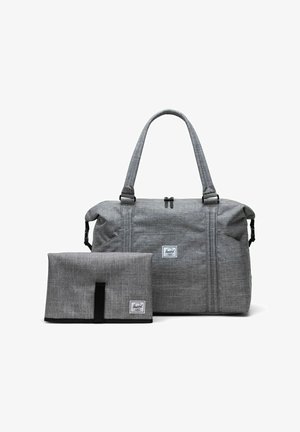 Sac de sport en tissu gris avec deux poignées supérieures et un matelas à langer plié assorti, tous deux portant des étiquettes de la marque Herschel.