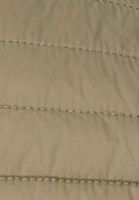 Gros plan sur un tissu beige avec des lignes horizontales cousues créant un motif matelassé.