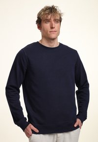 Felpa girocollo blu navy realizzata in tessuto morbido, con maniche lunghe e polsini a coste. Design semplice e minimalista senza loghi visibili.