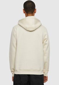 Cremfarvet hoodie lavet af blødt materiale, med en stor hætte og ribbede manchetter, vist fra ryggen, med en afslappet pasform.