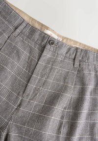 Gray plaid trousers with textured fabric, featuring a waistband with a button closure and subtle interior stitching details.