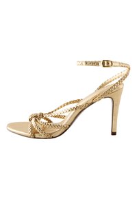 Sandale à talon haut dorée avec lanières tressées, bout ouvert et boucle à la cheville. Finition métallique avec texture lisse et design de talon fin.