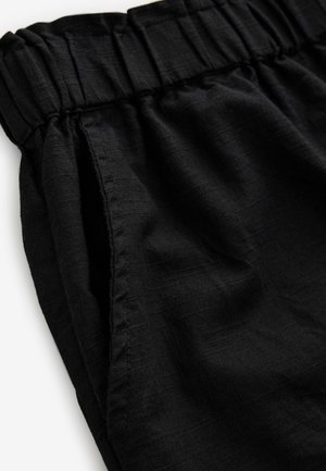 Pantaloni negri cu talie elastică, țesătură texturată și buzunare laterale, cu croială lejeră și un luciu subtil.