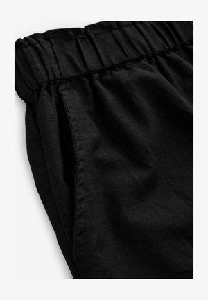 Sorte bukser med elastisk talje, tekstureret stof og sidelommer, med en løs pasform og en diskret glans.