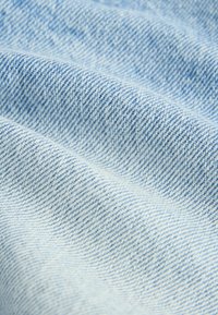 Tela de denim azul claro con un tejido de sarga, que presenta líneas diagonales sutiles y una superficie suave y texturada.