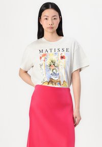 T-shirt gris à manches courtes avec un imprimé coloré de Matisse. Associé à une jupe en satin rose vif, mettant en valeur une texture et une coupe lisses.
