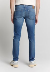 Skinny jeans in lichtblauwe denim. Heeft vijf zakken, minimale vervaging en een bruine leren label op de achterband. Textuurstof.