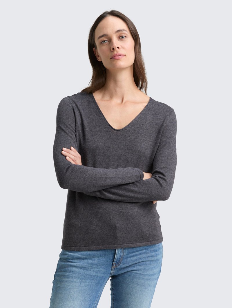 Suéter de manga larga gris oscuro con escote en V, textura suave y diseño ajustado. Combinado con jeans de color azul claro.