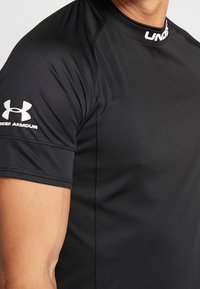 Svart atletisk skjorta i stretchmaterial med korta ärmar. Har rund hals och vitt logotyp på vänster axel.