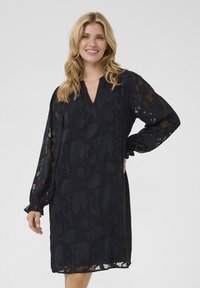 Must mustrikk dress lillelille mustritega, V-kaelusega, pikad volüümikad varrukad ja elastsed mansetid, luues lõdva silueti. Pehme tekstuur.