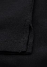 Černá látka s propletenými švy a přehnutým okrajem, která zvýrazňuje hladkou strukturu a bezproblémový design.