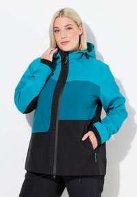 Veste imperméable teal et noire avec capuche, présentant une fermeture zippée à l'avant, des poignets élastiques et un logo de marque visible le long de la fermeture éclair.