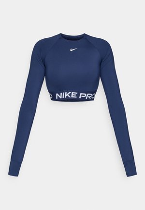 Haut cropped à manches longues Nike Pro en bleu marine. Présente un col rond et une bande logo avec "NIKE PRO" sur l'ourlet. Tissu lisse et extensible.