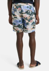 Mannen strandshorts van lichtgewicht stof met een tropische print, featuring palmbomen, zeilboten en hutten in levendige kleuren. Elastische tailleband.