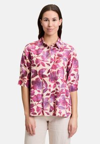 Kwiatowa bluzka z lekkiego materiału, z różowym i fioletowym wzorem liści, z kołnierzykiem, krótkimi rękawami i zapinaniem na guziki z przodu.