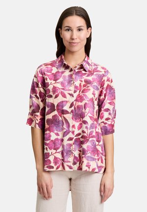 Bloemige blouse van lichte stof met een roze en paarse bladerenpatroon, kraagontwerp, korte mouwen en knoopsluiting aan de voorkant.
