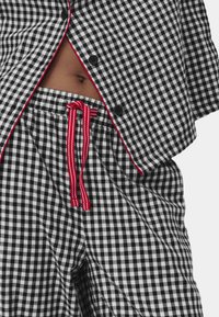 Sorte og hvide ternede pyjamas sæt med en kortærmet top og shorts med elastisk talje, rød snor og accent piping.