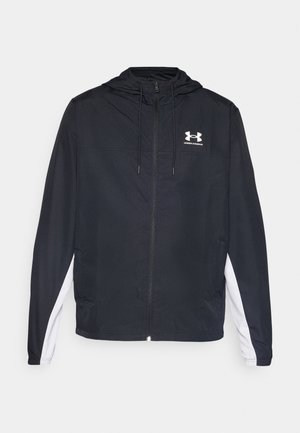 Sort atletisk jakke med hætte, lynlås lukning og hvide sidepaneler. Har et logo på brystet og elastiske manchetter for en sikker pasform.