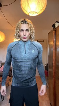 Tettsittende langermet termisk topp i mørkegrått med strukturert stoff, en halv glidelås og en liten logo på brystet, sammen med svarte shorts.