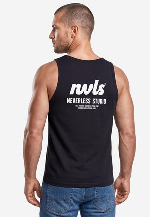 Man with short hair wearing a black sleeveless shirt with "nvls Neverless Studio" logo on back, paired with blue jeans, facing left.
