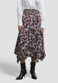 Bloemenrok met een hoge-lage zoom, met een witte basis en donkere rode en paarse patronen. Draagt met strakke zwarte enkellaarzen.