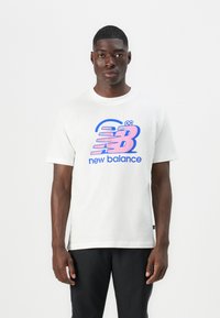 Hvid bomulds T-shirt med et stort pink og blåt "New Balance" logo, korte ærmer og en afslappet pasform med en rund halsudskæring.