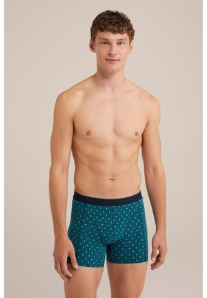 Boxers breves en tono teal, fabricados en una mezcla de algodón, con una cinturilla en navy y pequeños patrones geométricos en blanco por todo su diseño. Tienen un corte ajustado y de soporte.