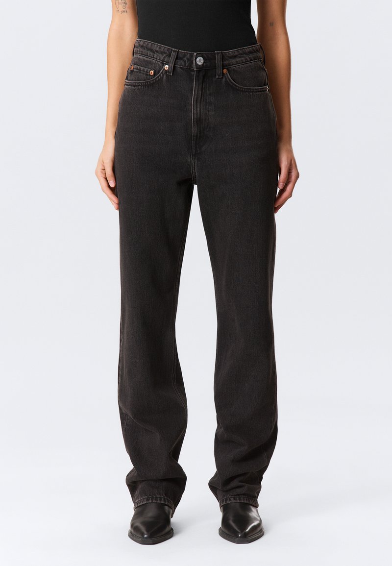 Calças de ganga pretas de cintura alta com corte de perna direita, tecido resistente, costuras subtis e cinco bolsos; fecho de botão e fecho éclair.