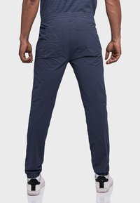 Navy Sporthosen mit elastischem Bund, zwei Gesäßtaschen und gerafften Bündchen. Der Stoff wirkt leicht und glatt.