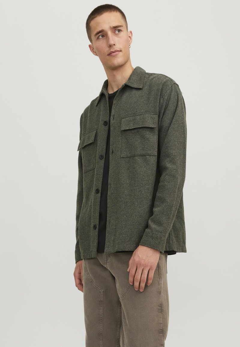 Camicia in flanella verde oliva con chiusura a bottoni, due tasche sul petto e colletto. Texture morbida e vestibilità rilassata.