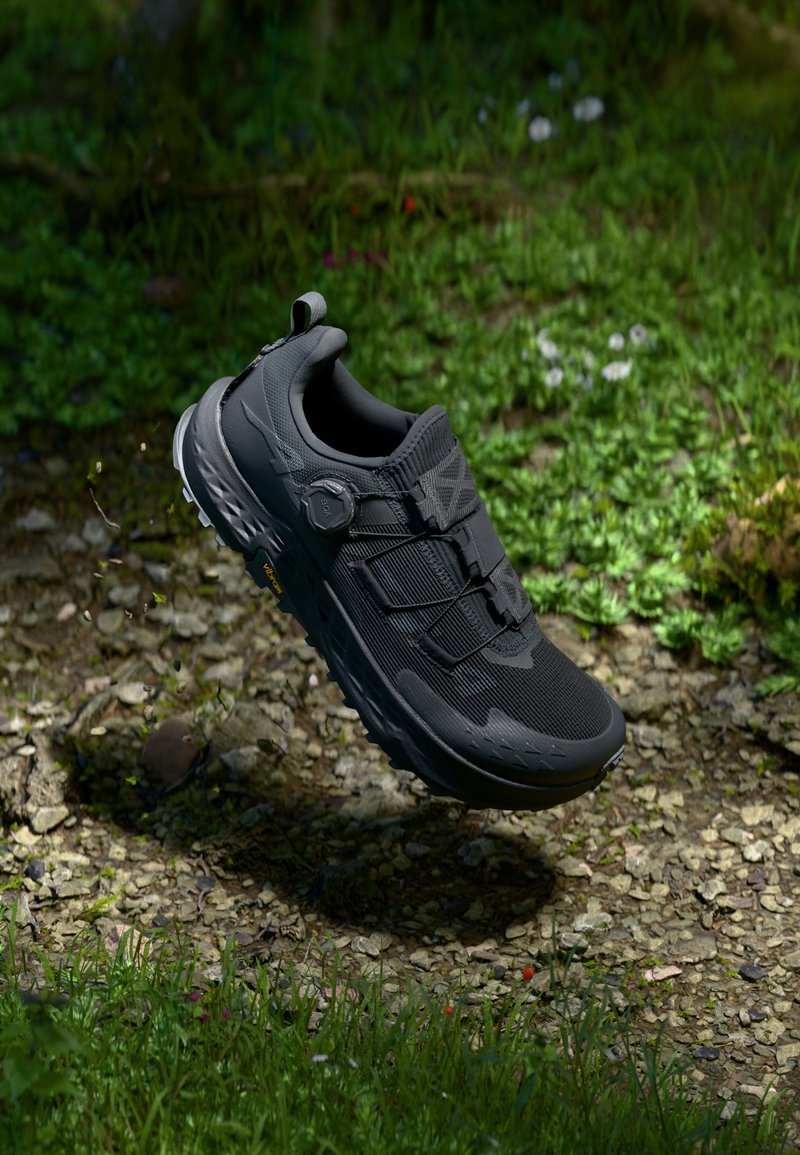 Black athletic shoe with textured upper, mesh accents, and a durable sole. Features a secure closure system and a pull tab at the heel.