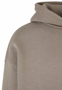 Sweat à capuche dans une couleur taupe clair, avec une coupe décontractée, une texture côtelée et un tissu doux et brossé, doté d'une capuche superposée.