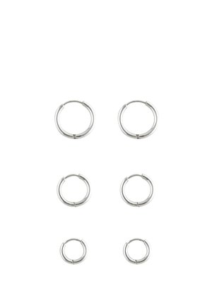 Silberne Creolen in drei Größen. Glatte metallische Oberfläche, abgerundete Form mit einer dezenten Naht. Einfaches Design, geeignet für verschiedene Stilrichtungen.