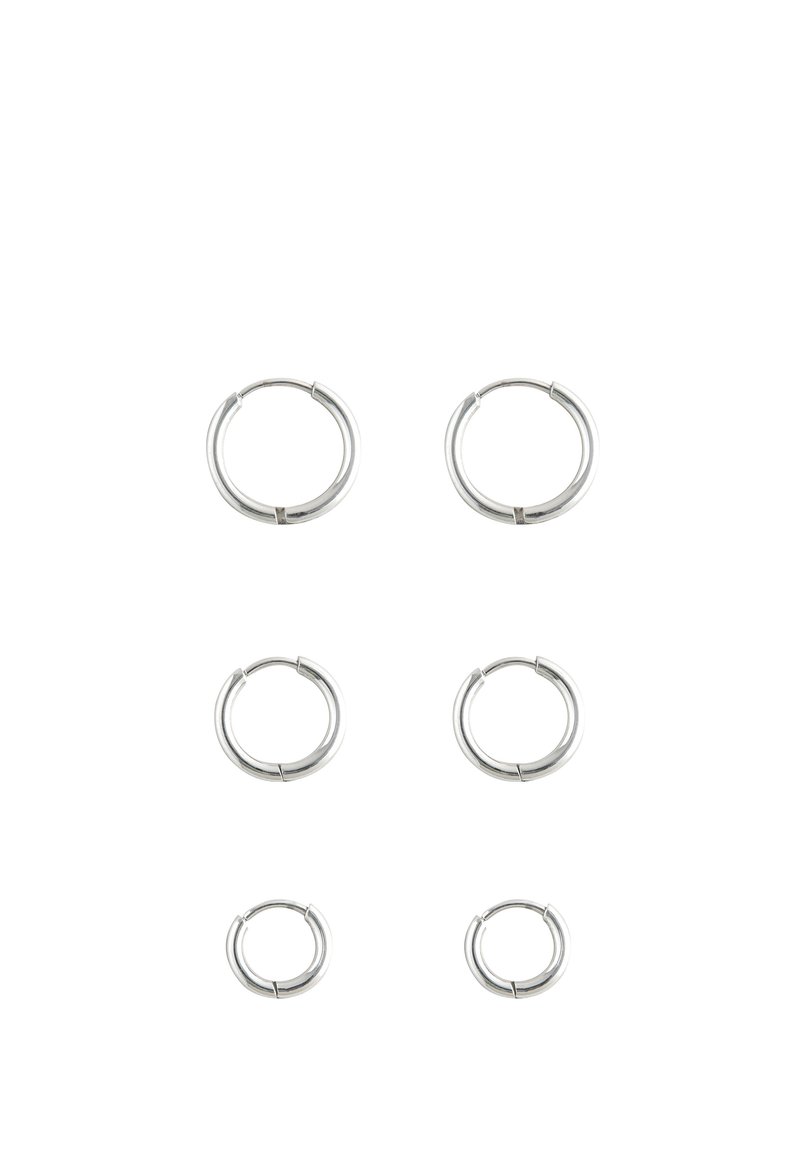 Silberne Creolen in drei Größen. Glatte metallische Oberfläche, abgerundete Form mit einer dezenten Naht. Einfaches Design, geeignet für verschiedene Stilrichtungen.