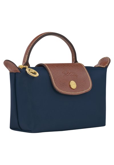 Navy blue nylon bag with a brown textured leather flap and handle, featuring gold hardware and a round logo accent.