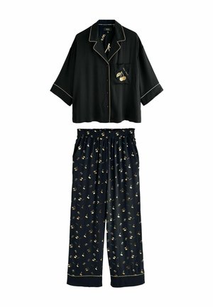 Zwart satijnen pyjama set bestaande uit een kort mouwige knooptop met een kersenprint zak en geprinte, elastische taillebroek met gouden accenten.