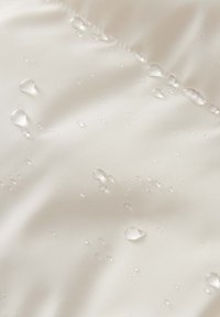 Wasserabweisender Stoff mit glatter Textur, der kleine Wassertropfen auf der Oberfläche zeigt und seine wasserdichten Eigenschaften hervorhebt.