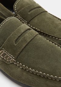 Olive drzewny zamszowe mokasyny z przeszyciami, charakteryzujące się designem w stylu mokasynów oraz miękką teksturą. Styl wsuwany z dekoracyjnymi detalami.