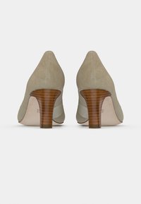 Escarpins en daim beige avec un bout pointu et un talon en bois rayé. Les semelles sont lisses et présentent des détails de marque subtils.