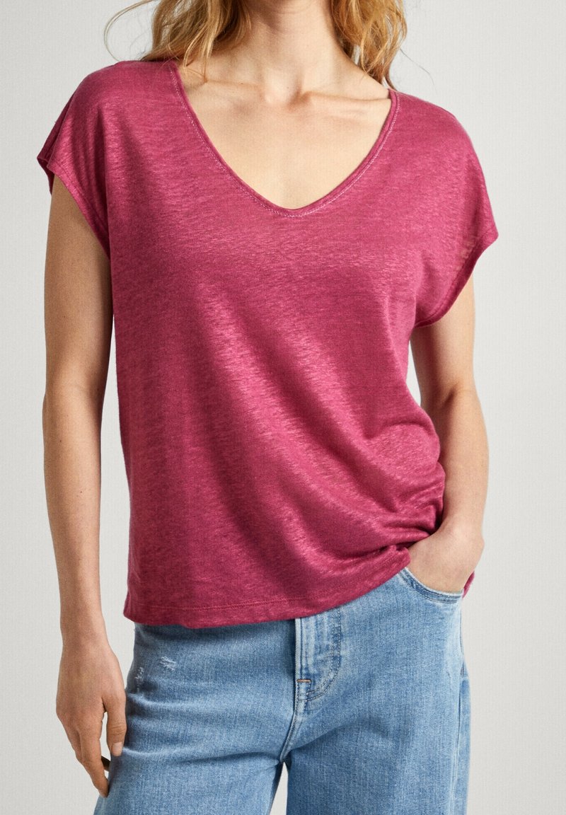 T-shirt a maniche corte, con scollo a V, di un morbido colore lampone mélange. Tessuto leggero con una vestibilità rilassata, indossato con jeans azzurri chiari.