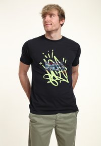 Camiseta negra de manga corta con un diseño gráfico de un camión y texto en estilo graffiti en tonos verdes y azules. Textura suave, estilo ajustado.