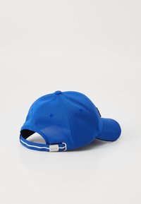 Zila beisbola cepure ar strukturētu formu, teksturētu audumu, regulējamu jostu un logotipa birku pie aizmugures.