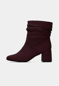 Μποτάκι μπορντό αστραγάλου με χαλαρή σχεδίαση, κατασκευασμένο από μαλακό συνθετικό υλικό, με φραγκόσυκο τακούνι και μυτερή μύτη.