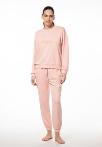 Roze sweatshirt en sweatpants set van zachte stof, met een ontspannen pasvorm. De bovenkant heeft een geprinte zin in een contrasterende kleur.