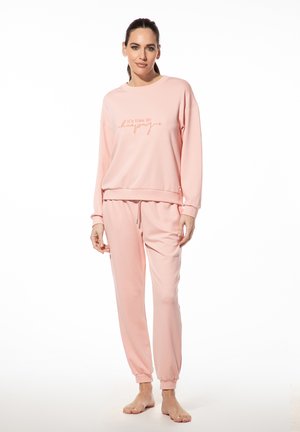 Roze sweatshirt en sweatpants set van zachte stof, met een ontspannen pasvorm. De bovenkant heeft een geprinte zin in een contrasterende kleur.
