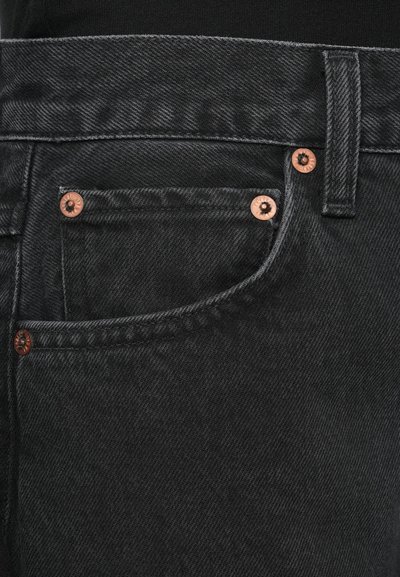 Μαύρο τζιν μεσαίας φωτεινότητας, με χαλκό χρώμα στα κουμπιά και τα φερμουάρ, με μπροστινή τσέπη και αντίθετη ραφή. Υφή υφάσματος με ελαφριά λάμψη.