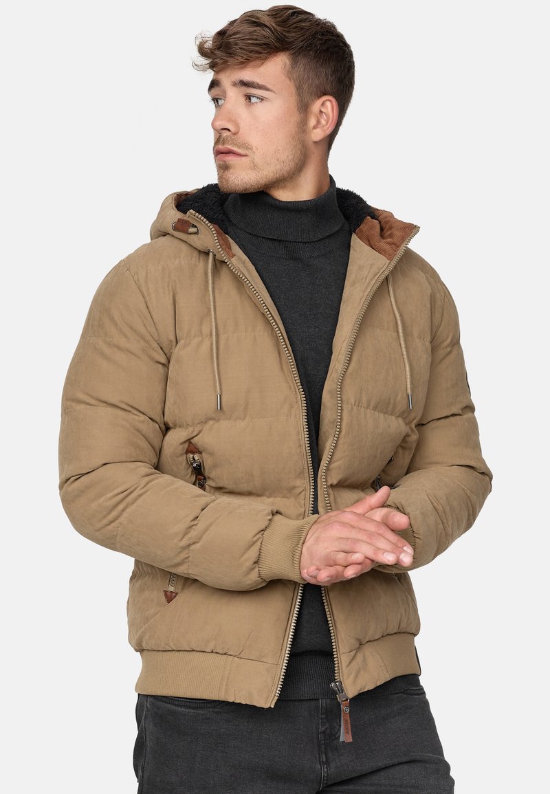 Chaqueta acolchada color caqui con cierre frontal, capucha ajustable, puños acanalados y forro interior texturizado. Cuenta con bolsillos laterales y detalles de cuero.